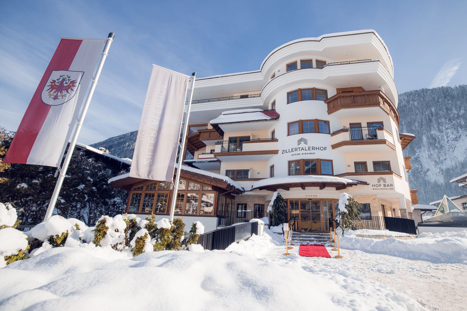 Det stilfulde 4-stjernede superior Zillertalerhof Alpine Hideaway ligger i skønne omgivelser, direkte i centrum af Mayrhofen. En skibus holder umiddelbart ved indkvarteringen og bringer gæsterne til Penken-banen (ca. 700 m fra indkvarteringen) eller til Ahorn-banen (ca. 1,1 km fra indkvarteringen). Løjpen og Zillertal-banens banegård ligger ca. 500 m fra indkvarteringen. Faciliteter Indkvarteringen har reception, Wi-Fi, elevator, morgenmadsrum, restaurant, bar, opholdsrum, bibliotek, vinkælder samt skidepot med støvlevarmer. Der er ligeledes gratis parkeringspladser (hvis ledig) samt en parkeringsgarage (mod betaling) og en ladestation til e-biler (mod betaling). Det omfattende og velholdte spa- og wellnessområde på ca. 2.000 m² har helårligt opvarmet indendørs- og udendørs pool, finsk sauna, øko-urte sauna og infrarød-sauna, dampbad, hvilezone med klangbrønd, opvarmede hvilebænke og tebar med frugt, nødder og "detox"-vandstation. På indkvarteringen er der mulighed for massager og skønhedsbehandlinger (mod betaling). Der tilbydes af og til også yoga- og meditationsprogrammer (se oplysninger på indkvarteringen). Man får en rabatkupon til udvalgte massage- og skønhedsanvendelser (indtil kl. 16) til en værdi af 10 ? pr. fuldt betalende gæst (kan ikke overdrages og kan ikke indløses i kontanter). Hotellet kan prale af flere priser, bl.a. Årets hotel 2021 (Gault & Millau). Forplejning 1/2 pensionen PLUS, der allerede er inkluderet i prisen, består af righoldig morgenmadsbuffet bl.a. med skiftende daglige specialiteter som fx "Weißwurst" og "Brezen", eksotiske frugter og mousserende vin eller "tyrolsk bondemarked". Mellem kl. 14 og 16 er der dagligt eftermiddags-"jause" med frisk frugt, "Sweet-Candy" buffet og søde retter. Om aftenen er der en 5-retters gourmet-menu med salat og ostebord. Derudover afholdes der løbende temabuffeter samt galla- og grillaftener. Der er også mulighed for gluten- og laktosefrie, vegetariske men også veganske retter.